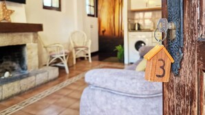 A cozy living room with a fireplace, a dining area, and a kitchen visible through an open door. - Apartment 3 (Pido)