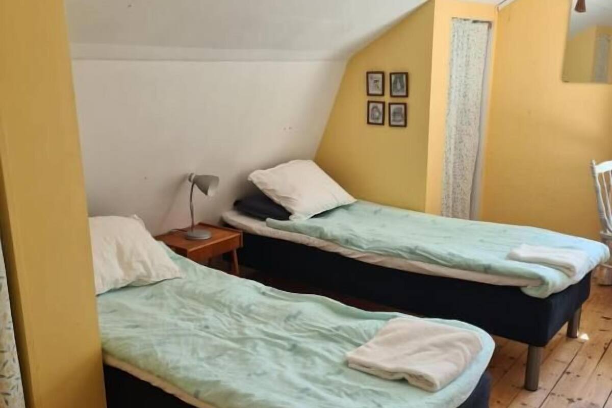 Una habitación con dos camas individuales, suelo de madera y techo inclinado.