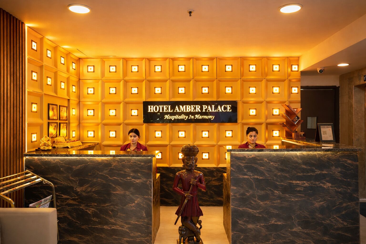 A reception area with a sign reading "HOTEL AMBER PALACE Hospitality In Harmony".