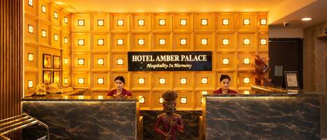 Una zona de recepción con un cartel que dice "HOTEL AMBER PALACE Hospitalidad en Armonía".