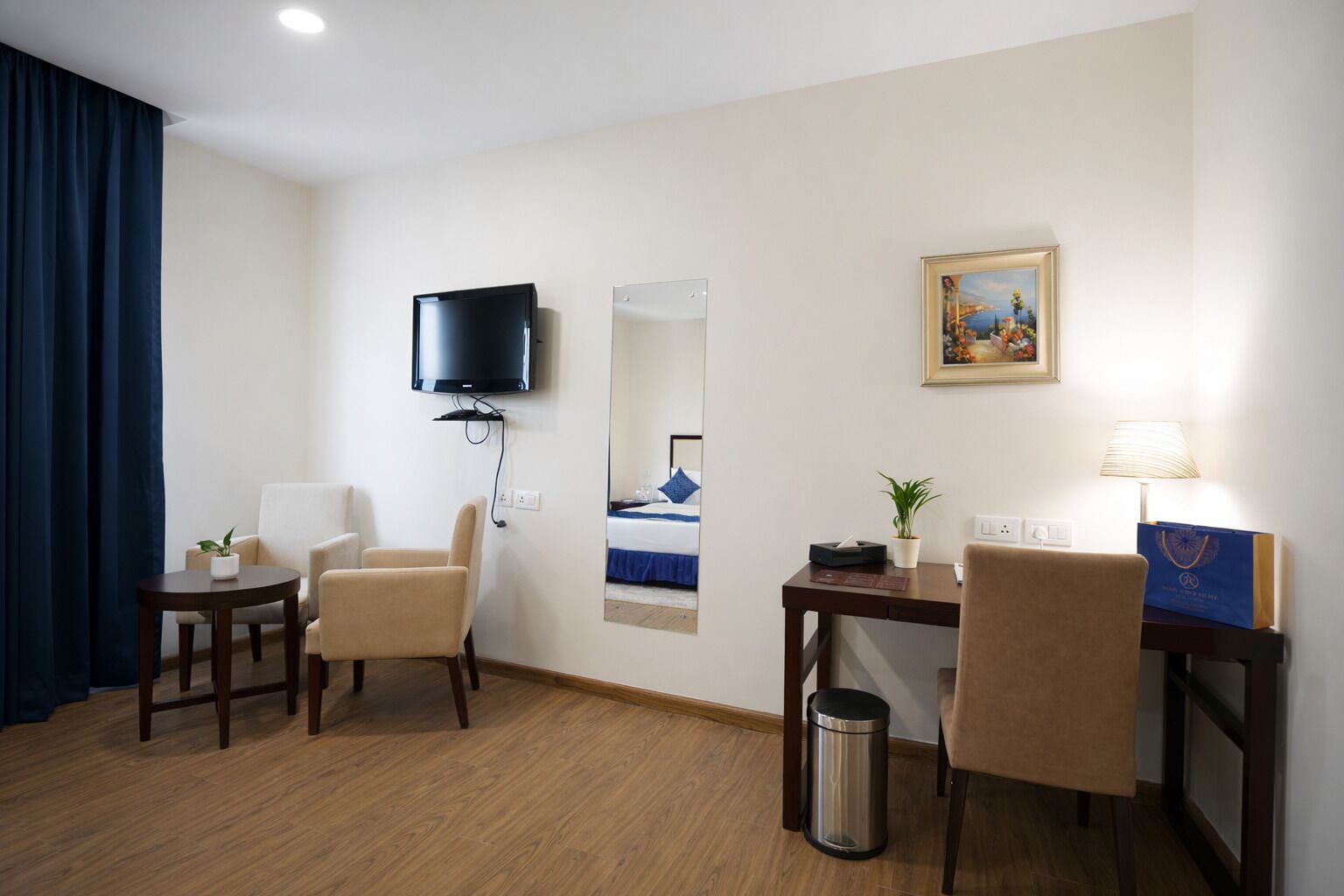 Une chambre d’hôtel équipée d’un lit, d’une télévision, d’un bureau, d’une chaise, d’une lampe et d’une poubelle.