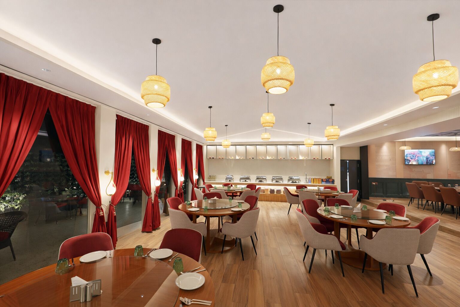 A modern dining area with round tables, red curtains, and hanging pendant lights.