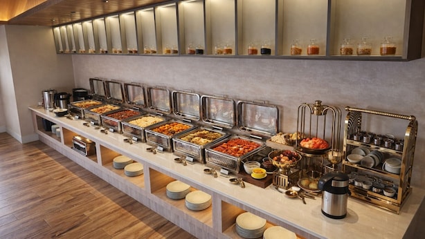 A buffet setup with various food items and utensils. - Hotel Amber Palace (Gurugram)