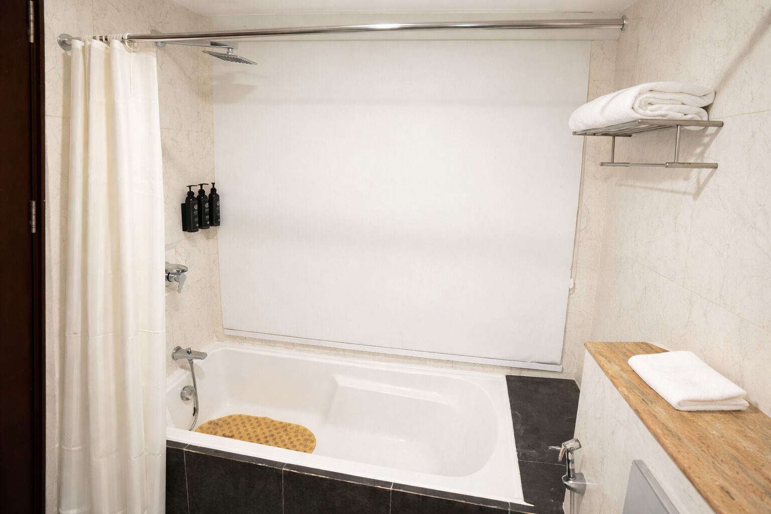 Een badkamer met een bad, douche en handdoekhouder.