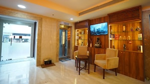A lobby with a marble floor, a reception desk, a television, and a display of awards and trophies. - Hotel Amber Palace (Gurugram)