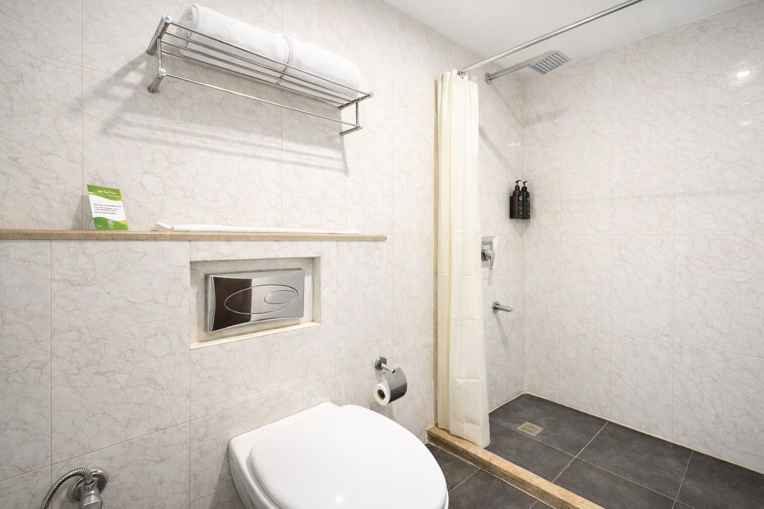 Un baño moderno con inodoro, ducha y perchero para toallas.