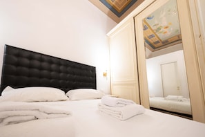 A hotel room with a large bed, a black headboard, white bedding, and a neatly folded towel on the bed. - Astonishing 2BR in Centric in Florencia (Florence)