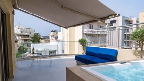 A balcony with a blue sofa, a hot tub, and a table with chairs. - Irakleio Notos Boutique Aprtmnts 3 Private Jacuzzi (Heraklion)