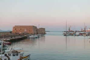 Un'antica fortezza in pietra affacciata su un tranquillo porticciolo con imbarcazioni ormeggiate.