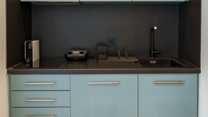 A compact kitchen with teal cabinets, a black countertop, and a built-in stove. - Irakleio Notos Boutique Aprtmnts 3 Private Jacuzzi (Heraklion)