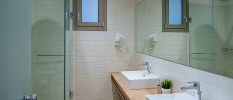 A modern bathroom with a glass shower enclosure, two sinks, and a large mirror.