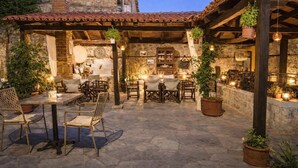 An outdoor patio with stone flooring, wooden furniture, and hanging plants. - Hagiati Karanos - Edessa Cozy Mountain Retreat (Edessa)