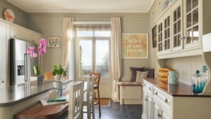 A kitchen with a wooden counter, white cabinets, a dining area with chairs, a window with curtains, and a wall with a framed quote. - Whitbarrow Lodge Ridgestone (Grange-over-Sands)