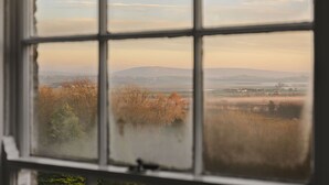 A view through a window with a grid pattern, displaying a landscape with trees and distant hills. - Whitbarrow Lodge Ridgestone (Grange-over-Sands)