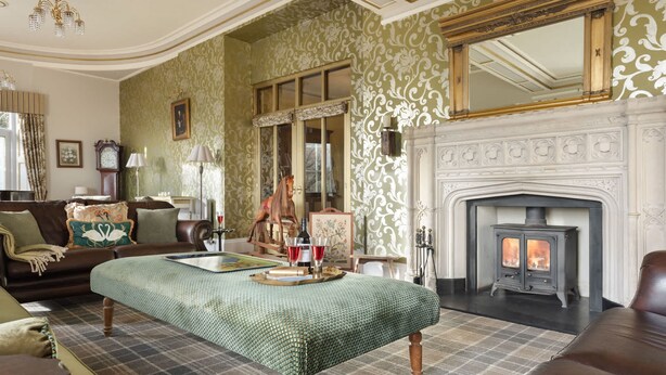 A traditional living room with a fireplace, green patterned wallpaper, and classic furniture. - Whitbarrow Lodge Ridgestone (Grange-over-Sands)