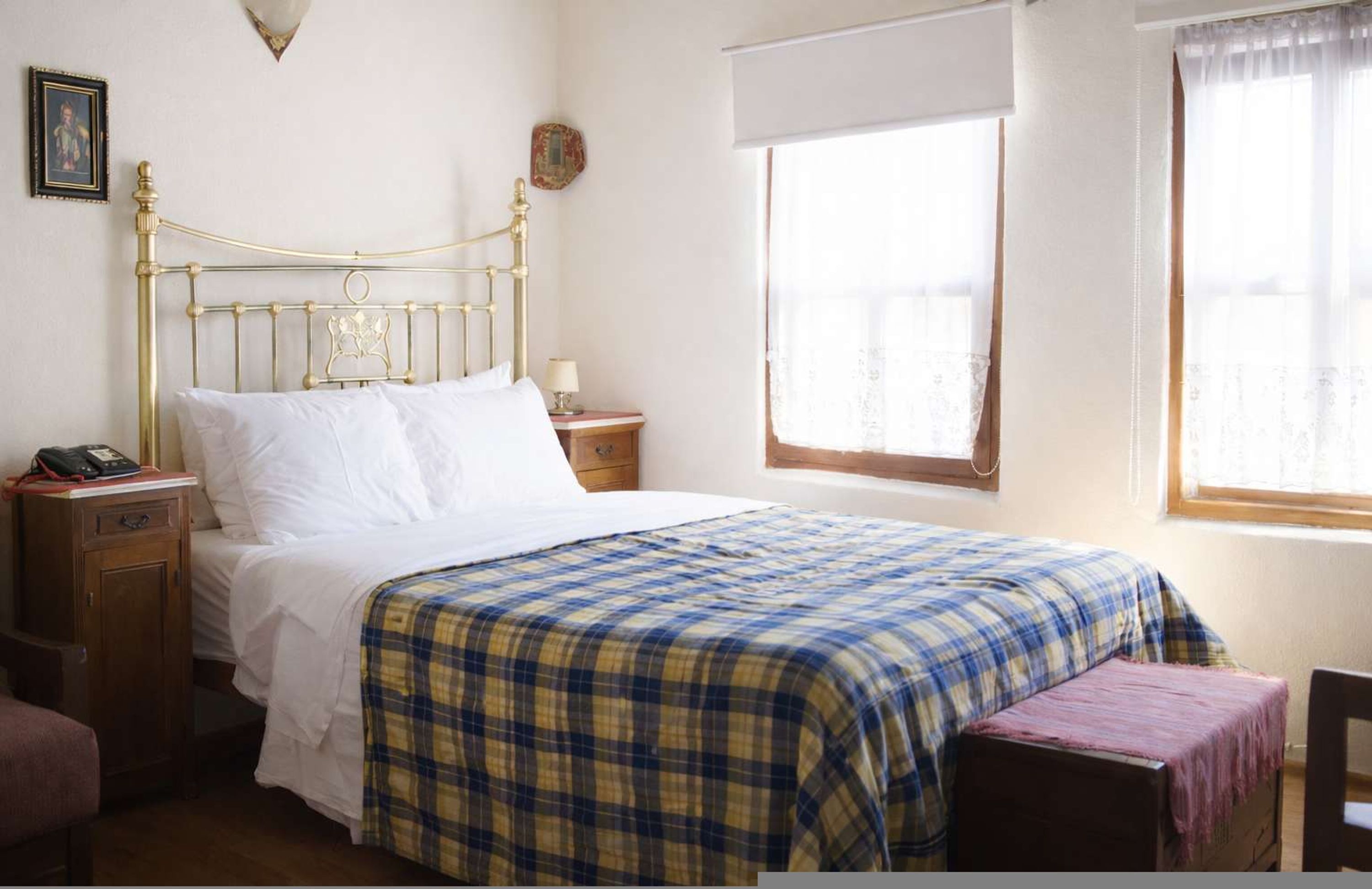 Un dormitorio con cama, mesita de noche y ventana con cortinas.
