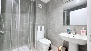 A modern bathroom with a glass shower enclosure, a toilet, and a pedestal sink. - Entire Flat in Greater London, United Kingdom (London)