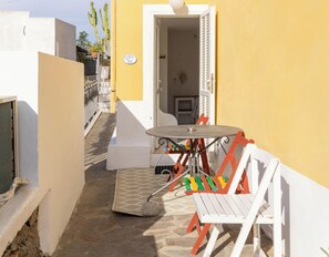 A small outdoor patio area with a table and chairs, a door leading to an interior space, and a yellow wall.