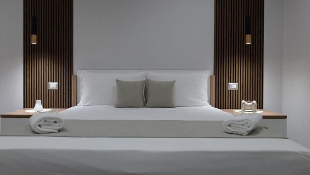 Une chambre d’hôtel moderne avec un grand lit, deux tables de chevet et un mur décoratif en bois.