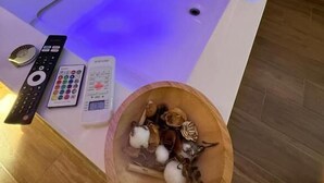 Une salle de spa moderne dotée d’un plancher chauffant, d’un bol en bois contenant des sels de bain et d’une télécommande.