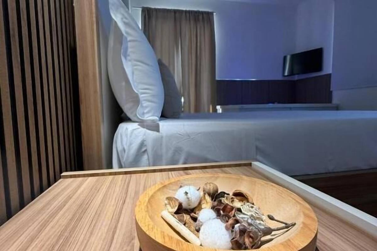 A hotel room with a bed, a TV mounted on the wall, and a wooden table with a bowl of snacks.
