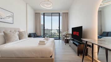 Ein modernes Hotelzimmer mit einem großen Bett, einem Schreibtisch, einem Fernseher und einem Balkon mit Blick auf die Stadt.