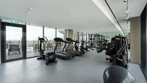 A modern gym with treadmills, elliptical machines, and weightlifting equipment. - Chic Studio Cinema & Game Room in Arjan (Dubai)