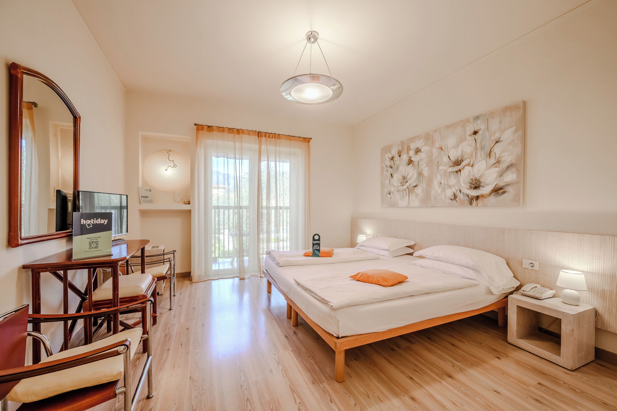 A hotel room with a bed, bedside table, lamp, and a large mirror.