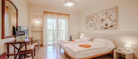 A hotel room with a bed, bedside table, lamp, and a large mirror.