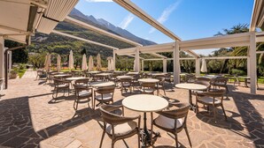 Een terras buiten met rieten meubilair en uitzicht op bergen.