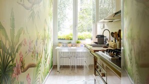 Una cocina con armarios blancos, una estufa y una ventana con vistas al verdor.