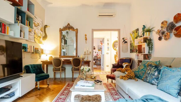 Una sala de estar con sofá, televisor, estantería y objetos decorativos.