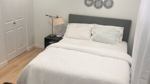 A bedroom with a large bed, a bedside table with a lamp, and a wardrobe. - A gorgeously cozy 1-bedroom apartment to keep you comfy while you enjoy Regina (Regina)