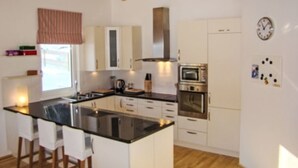 Een moderne keuken met witte kasten, een zwart aanrecht en een houten plafond.
