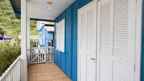 Une véranda couverte avec un plancher en bambou, des portes blanches et des murs bleus.