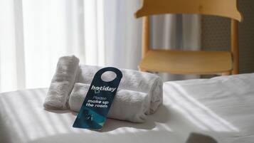 Ein ordentlich bezogenes Bett mit gefalteten weißen Handtüchern und einem Etikett am Bett.