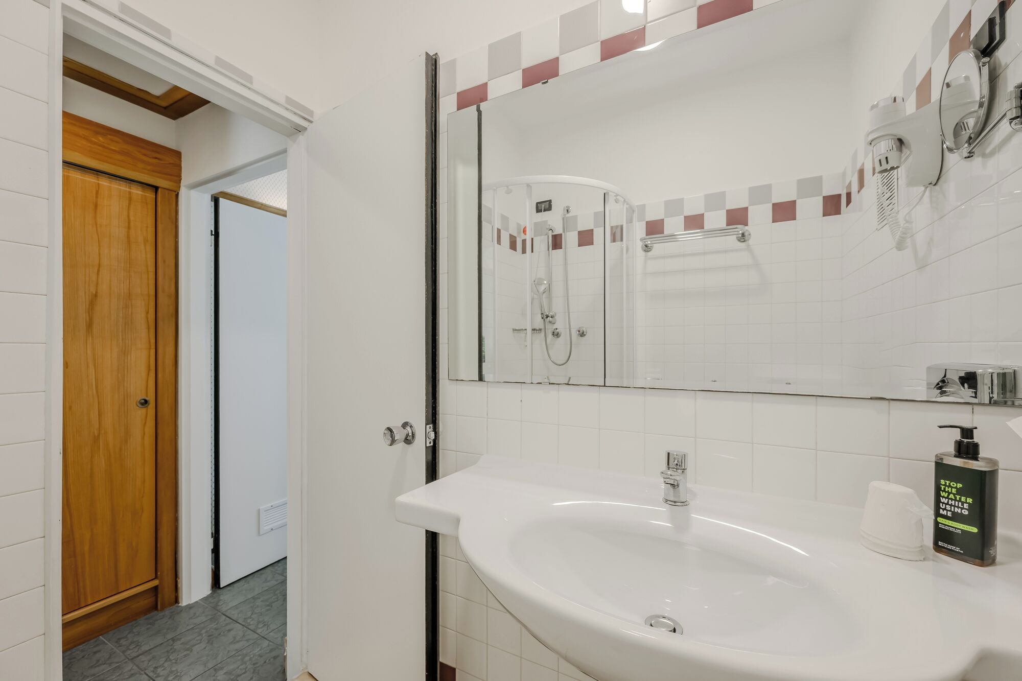Ein Badezimmer mit großem Spiegel, Waschbecken und Dusche.