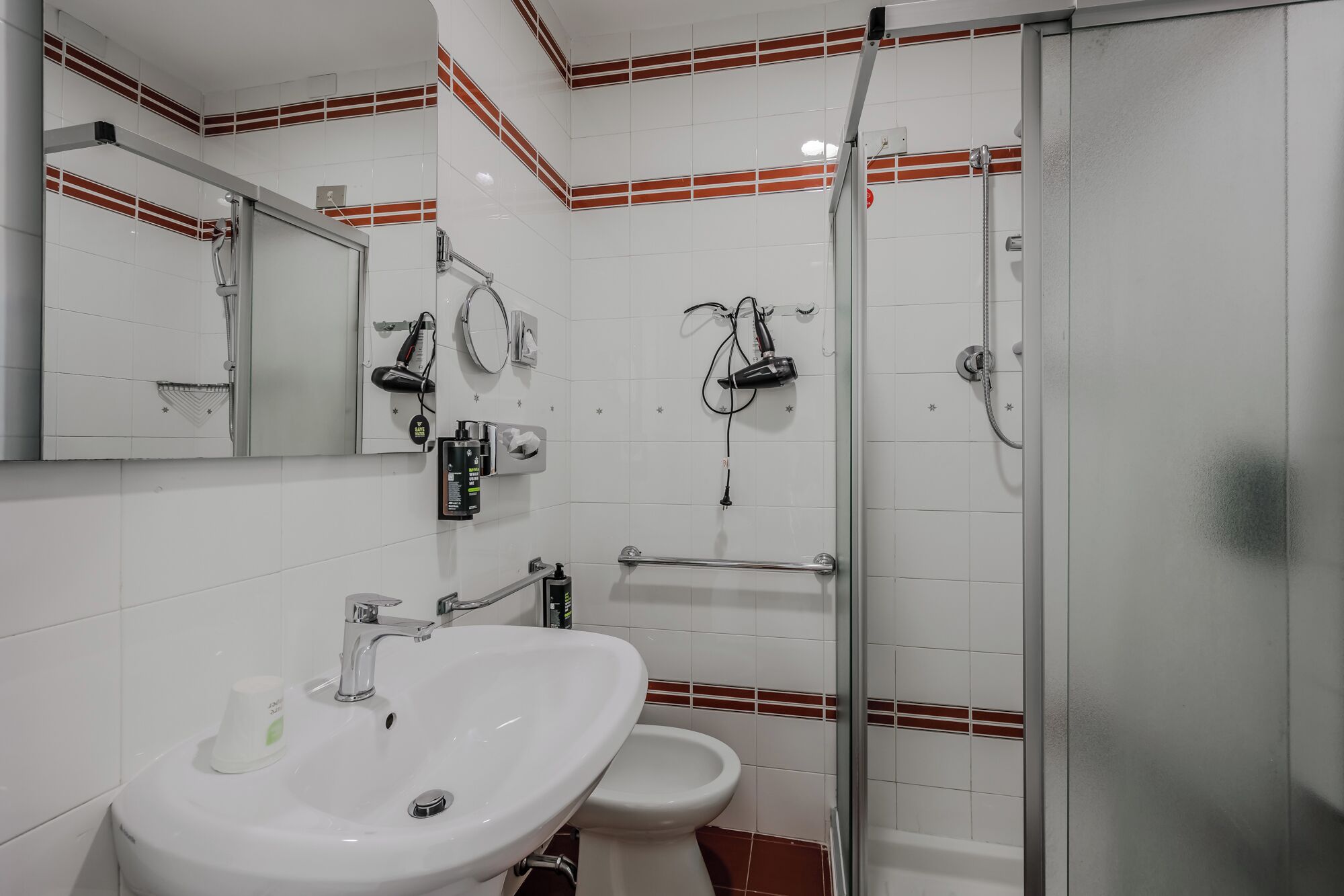 Ein Badezimmer mit Waschbecken, Spiegel, Toilette und Dusche.