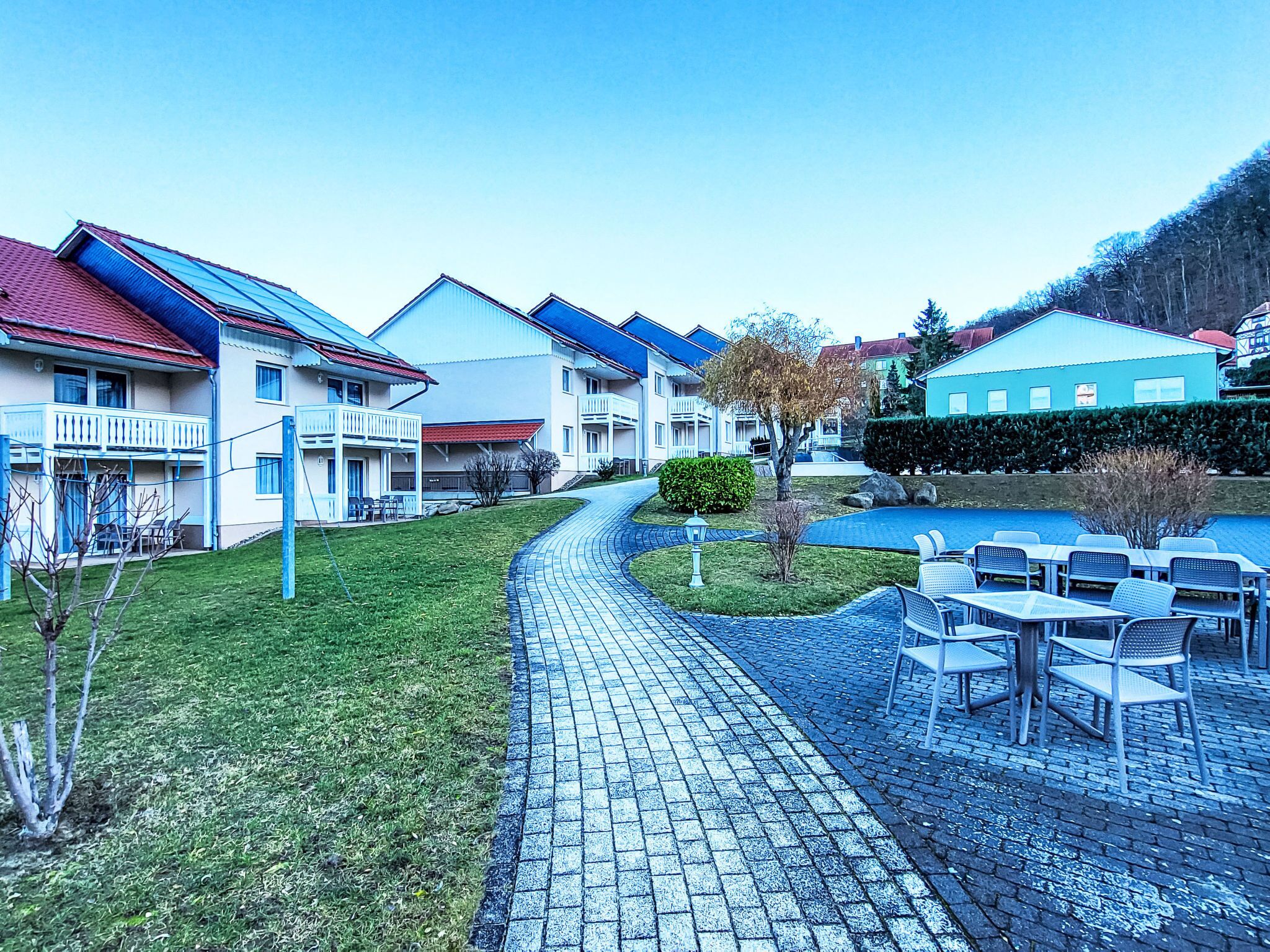 Ein Wohngebiet mit Häusern, einem gepflasterten Weg und Sitzgelegenheiten im Freien.