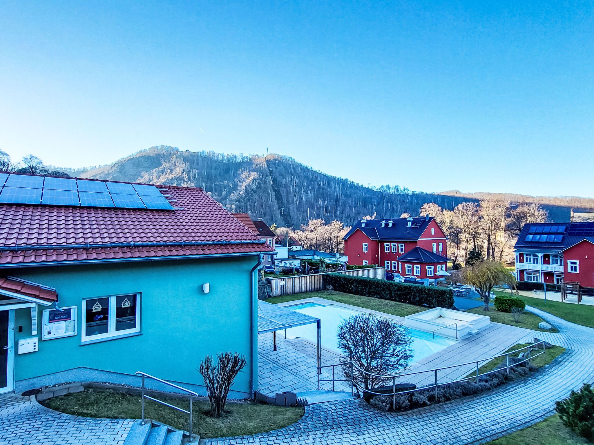 Ein Wohngebiet mit Schwimmbad, Solaranlagen und Häusern mit roten Dächern.