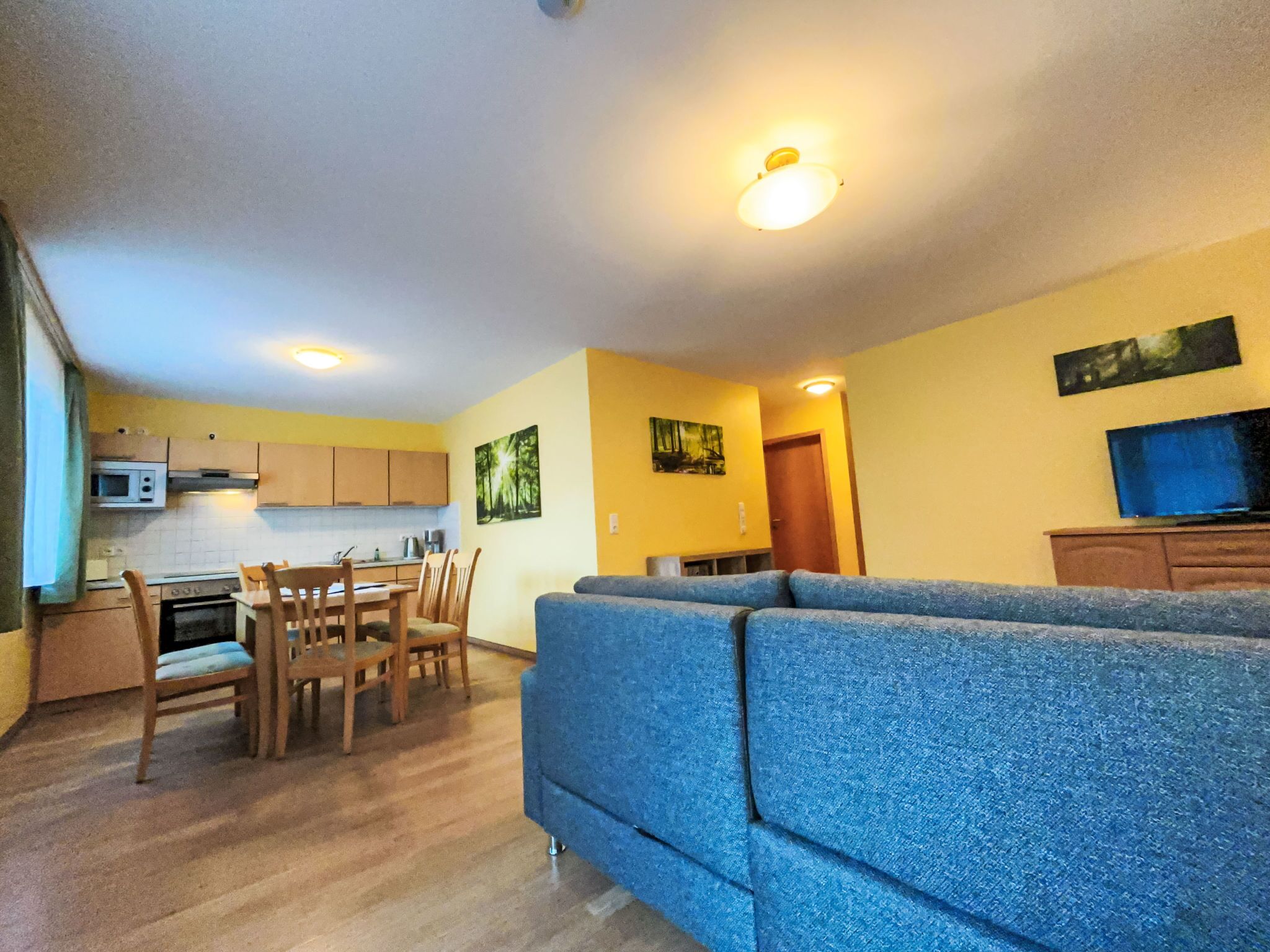 Un espacio habitable compacto con kitchenette, comedor y zona de estar con sofá.