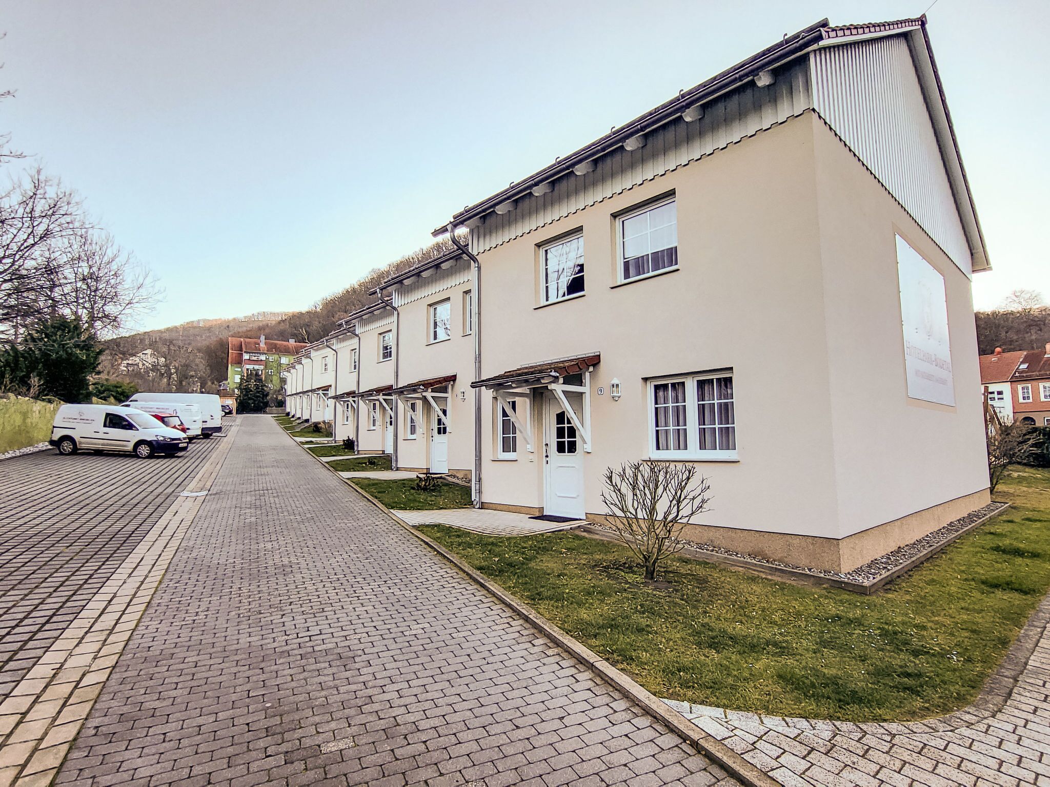 Eine Reihe moderner, zweigeschossiger Gebäude mit einheitlicher Fassade, einem gepflasterten Weg und einer kleinen Rasenfläche.