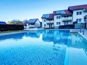 A swimming pool with a tiled floor, surrounded by buildings with solar panels on the roofs. - Hotelpark Bodetal by Interhome (Thale)