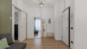 Een modern interieur met een houten vloer, een bank, een hanglamp en een deur met een telefoon.