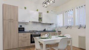 Een moderne keuken met witte kastjes, een eettafel met stoelen en een raam met gordijnen.