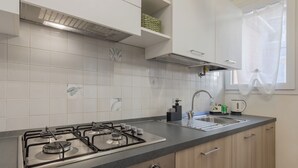 Een moderne keuken met een gasfornuis, een spoelbak en een raam met een lichtdoorlatend gordijn.