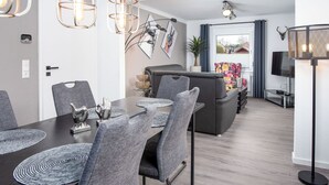 Een moderne eetruimte met een donker houten tafel, grijs gestoffeerde stoelen en decoratieve metalen verlichtingsarmaturen.