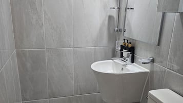 Un baño moderno con inodoro, lavabo y ducha.