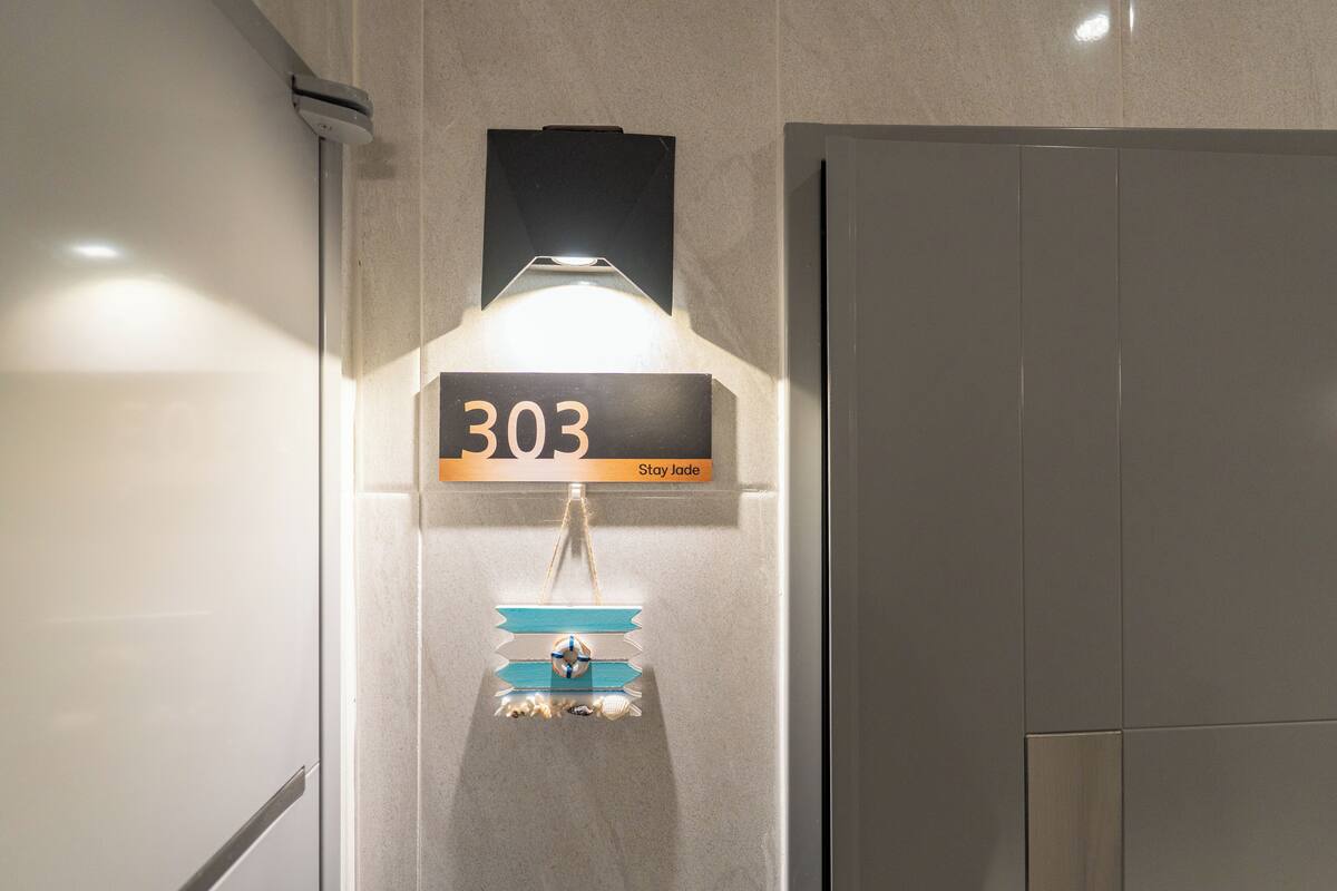 A wall-mounted sign with the number '303' and the text 'Stay jade.'