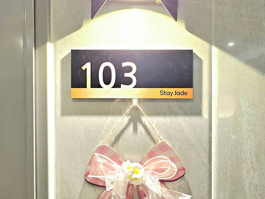 A room number sign with '103 Stay Jade' and a decorative bow with flowers.